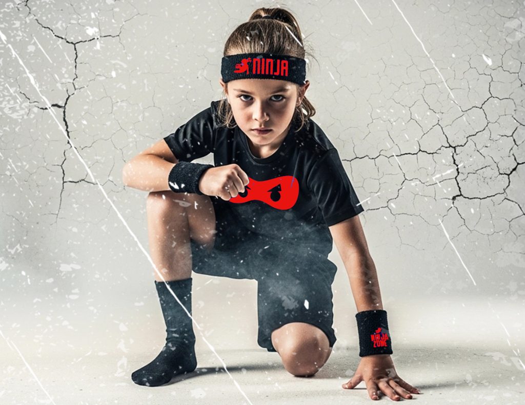 Young NinjaZone participant crouching in a black uniform with a red headband
