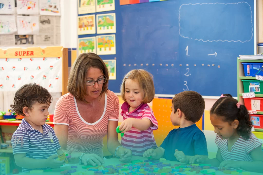 Teacher and children playing at a classroom table