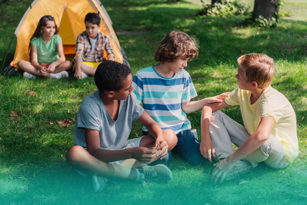 Camp counselor reading with children outdoors