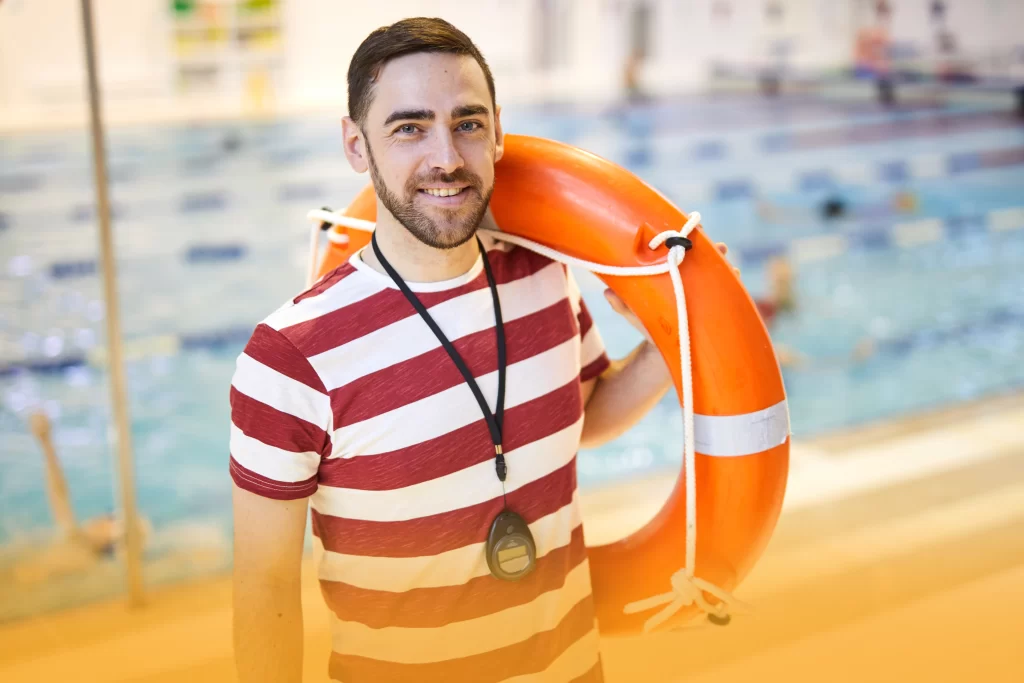 Lifeguard beside the pool holding rescue equipment