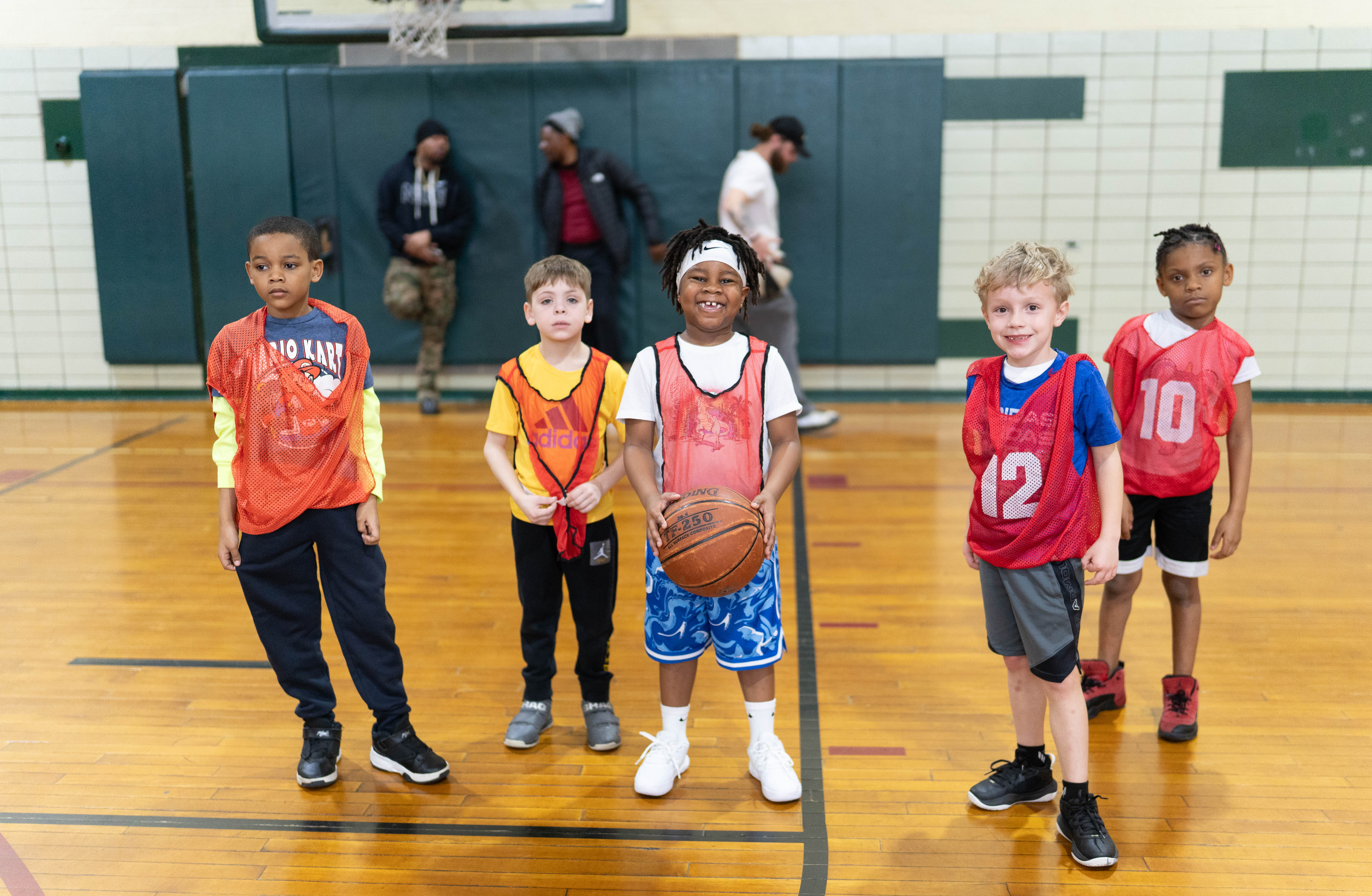 Five young YMCA basketball teammates posing together on the court