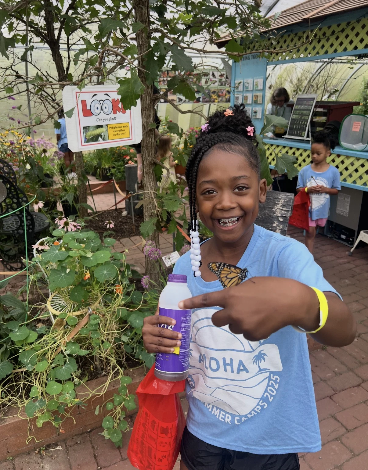 A smiling Central day camper holding a butterfly on her hand