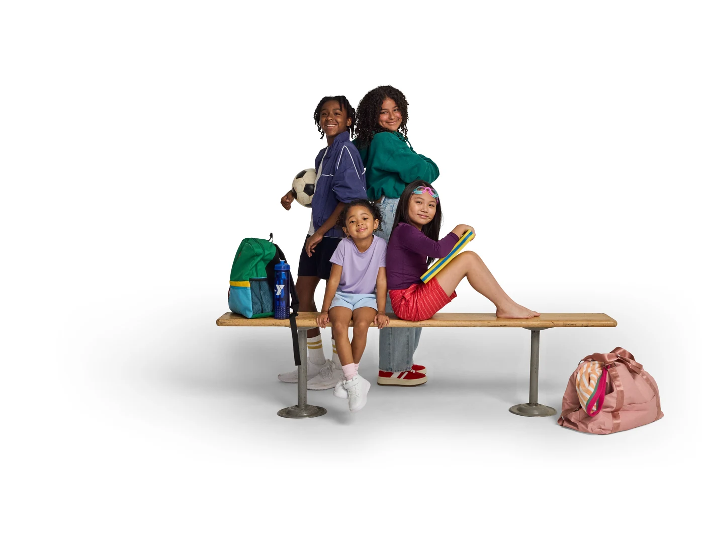Four children gathered around a bench with a soccer ball and swimming equipment