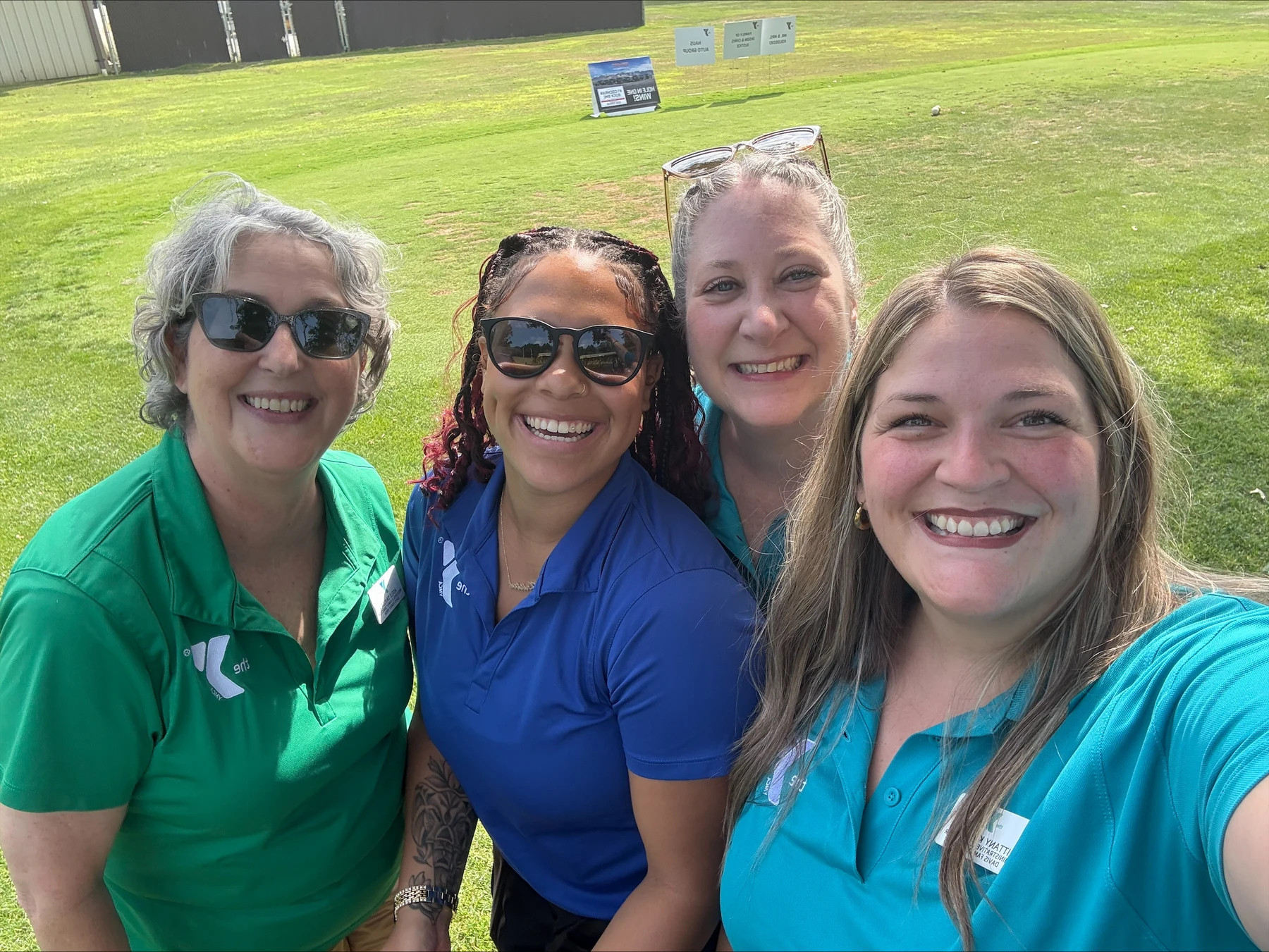 Four YMCA staff members smiling together outdoors on a sunny lawn